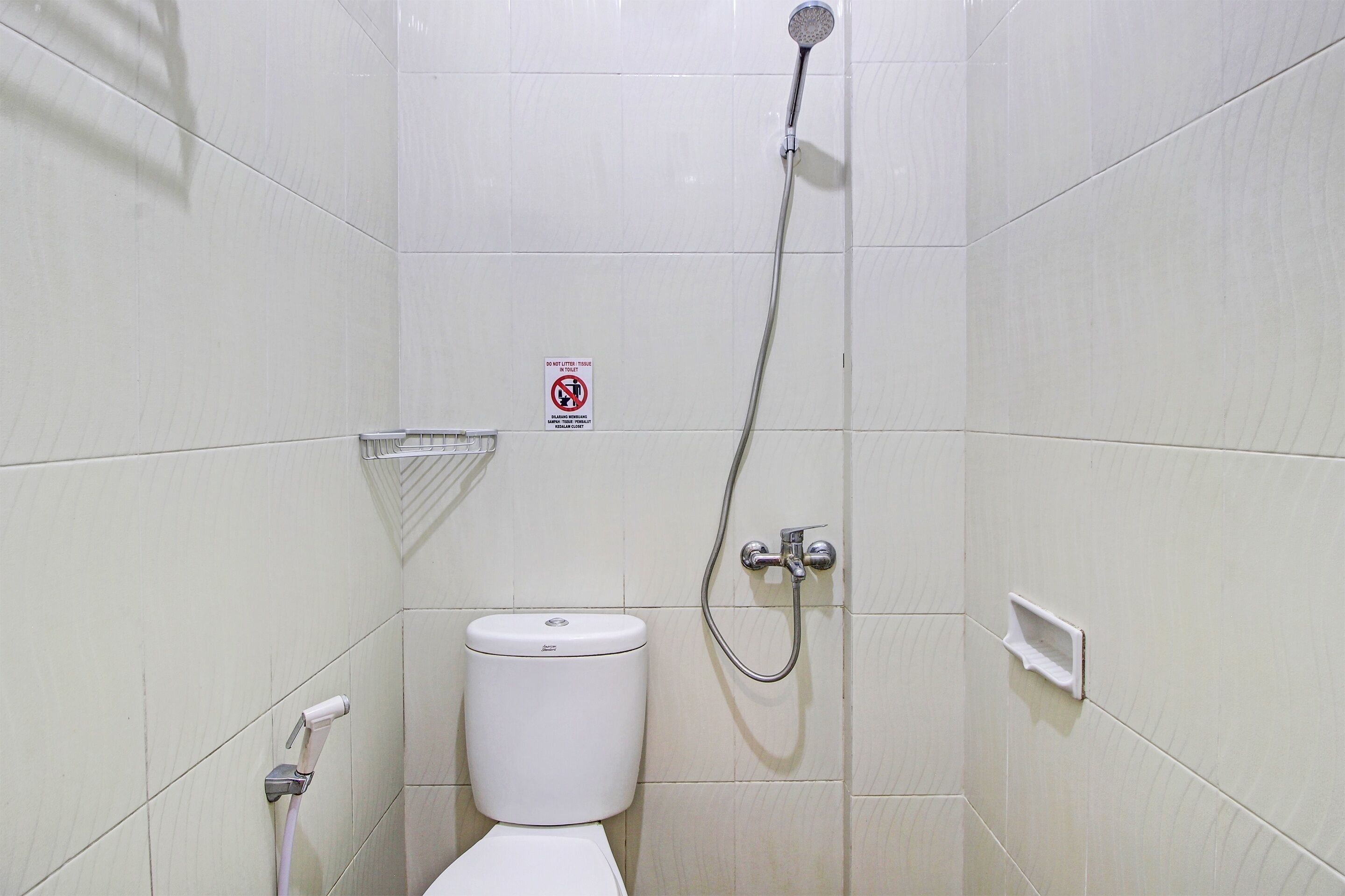 A small, white-tiled bathroom with a toilet, a shower, and a hand dryer.