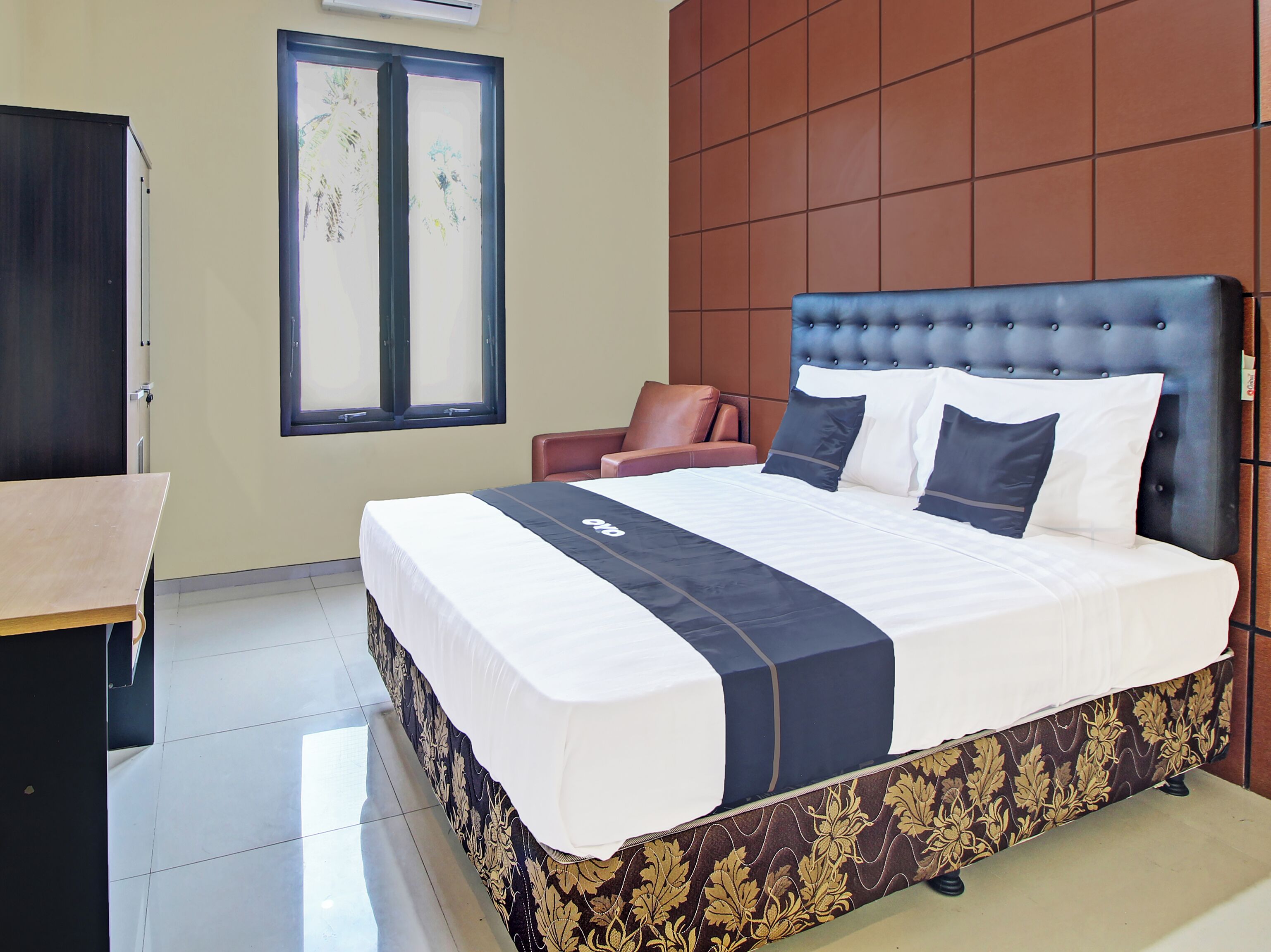 Hotelkamer met een groot bed, een bureau, een stoel, een raam en een wandairconditioner.