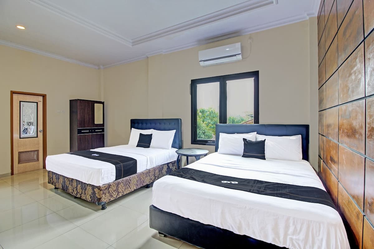 A hotel room with two beds, a small round table, a wardrobe, and an air conditioning unit.