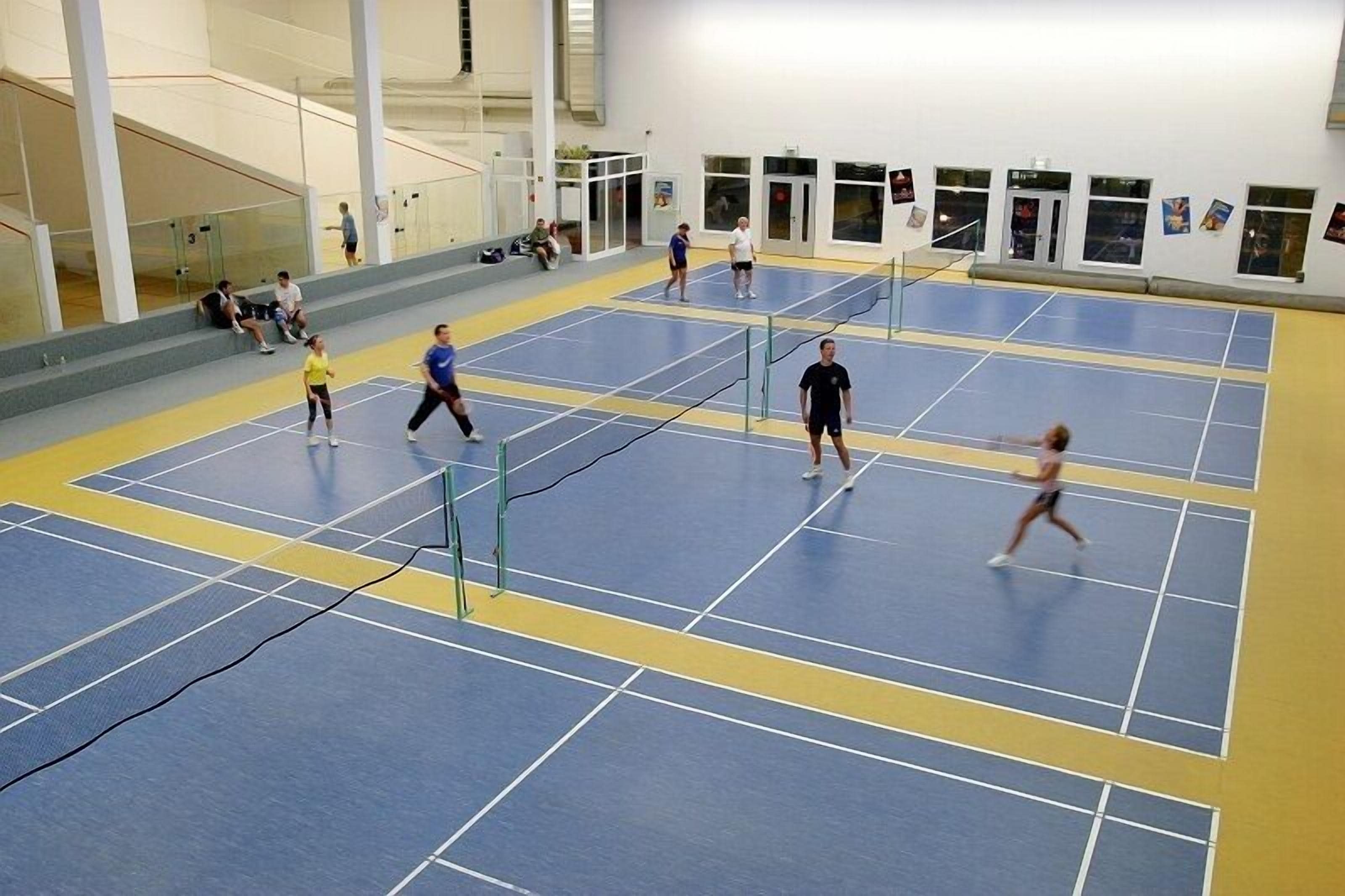 Een binnentennisbaan met meerdere spelers en toeschouwers.