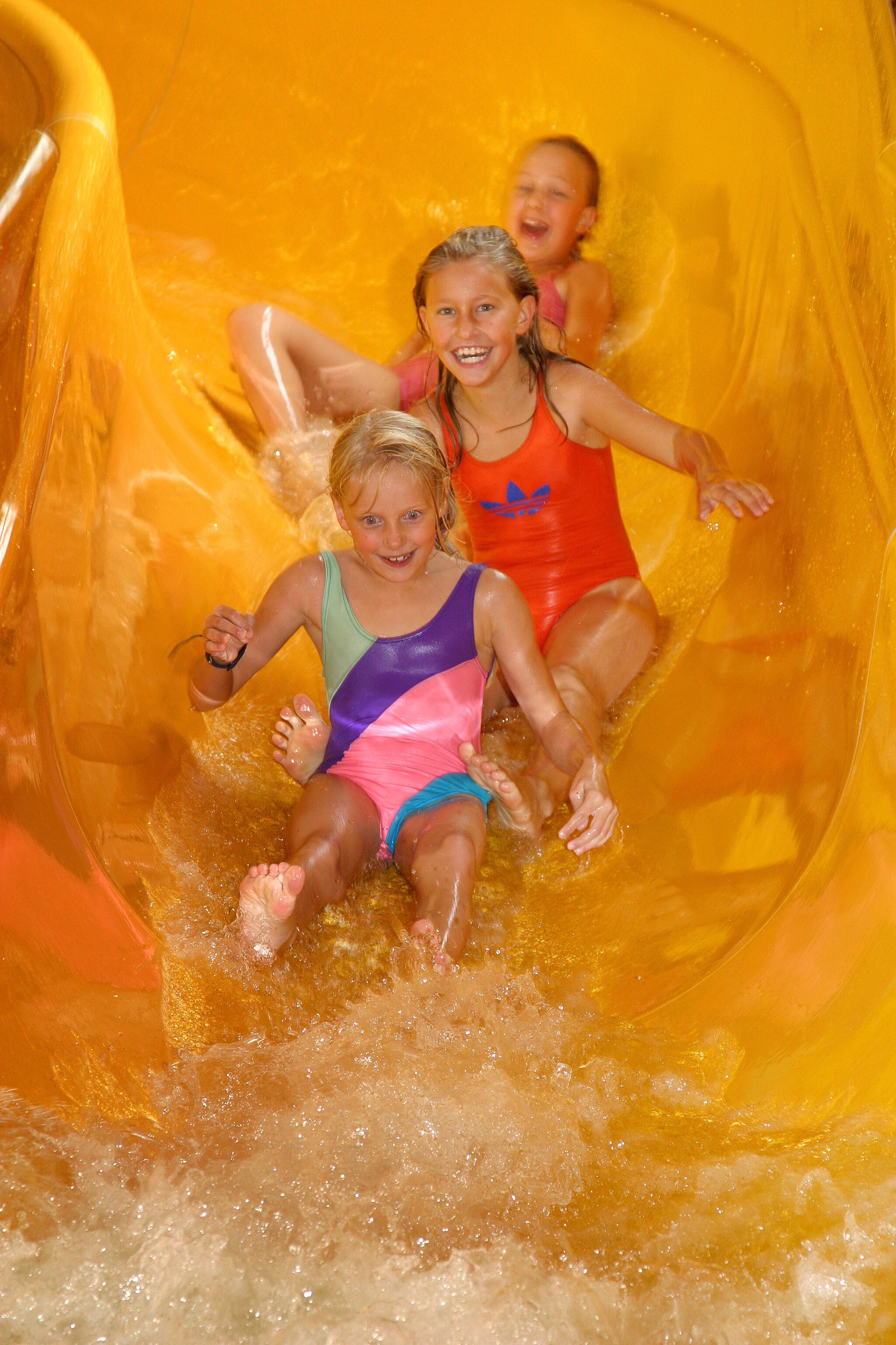 Children sliding down a yellow water slide.
