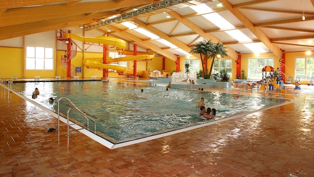 An indoor swimming pool with multiple lanes, a water slide, and a play area. - Sporthotel Neuruppin - Apartmenthaus mit Ferienwohnungen (Neuruppin)