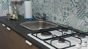 Una cocina con estufa a gas, pileta y protector de salpicaduras estampado.