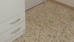 Una habitación con un armario blanco, una puerta cerrada y piso de baldosas.
