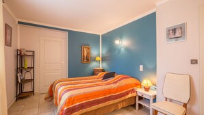 Un dormitorio con cama, mesita de noche, silla y lámpara de pared.