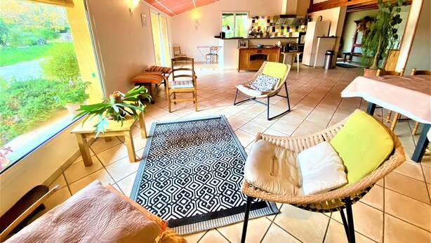 Un salón espacioso con un ventanal grande, una mesa de comedor y una cocina al fondo.