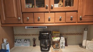 A kitchen with wooden cabinets, a coffee maker, and various kitchen items on the counter. - Cozy private room in shared residence with pool (San Juan)