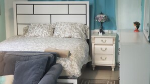 A neatly arranged bedroom with a bed, bedside table, lamp, and dresser. - Cozy private room in shared residence with pool (San Juan)