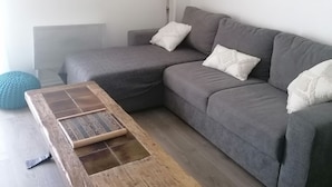 A modern living room with a grey sectional sofa, a wooden coffee table, and a round wall decoration.