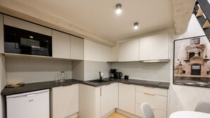 Una cocina moderna con armarios blancos, un microondas negro y una cafetera.