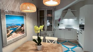 Una cocina moderna con armarios blancos, una mesa de comedor de madera y un amplio ventanal con vistas a un paisaje pintoresco.