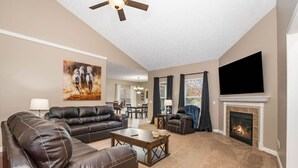 Ein Wohnzimmer mit Kamin, Ledersofas, einem Couchtisch und einem Flachbildfernseher.