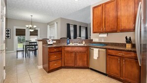 Eine moderne Küche mit Holzausstattung, einem Edelstahlkühlschrank und einem Essbereich mit einer Kronleuchter.