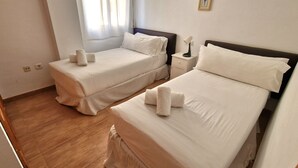 A hotel room with two beds, each with neatly folded towels and white linens. - Apartamentos Latin  (Nerja)