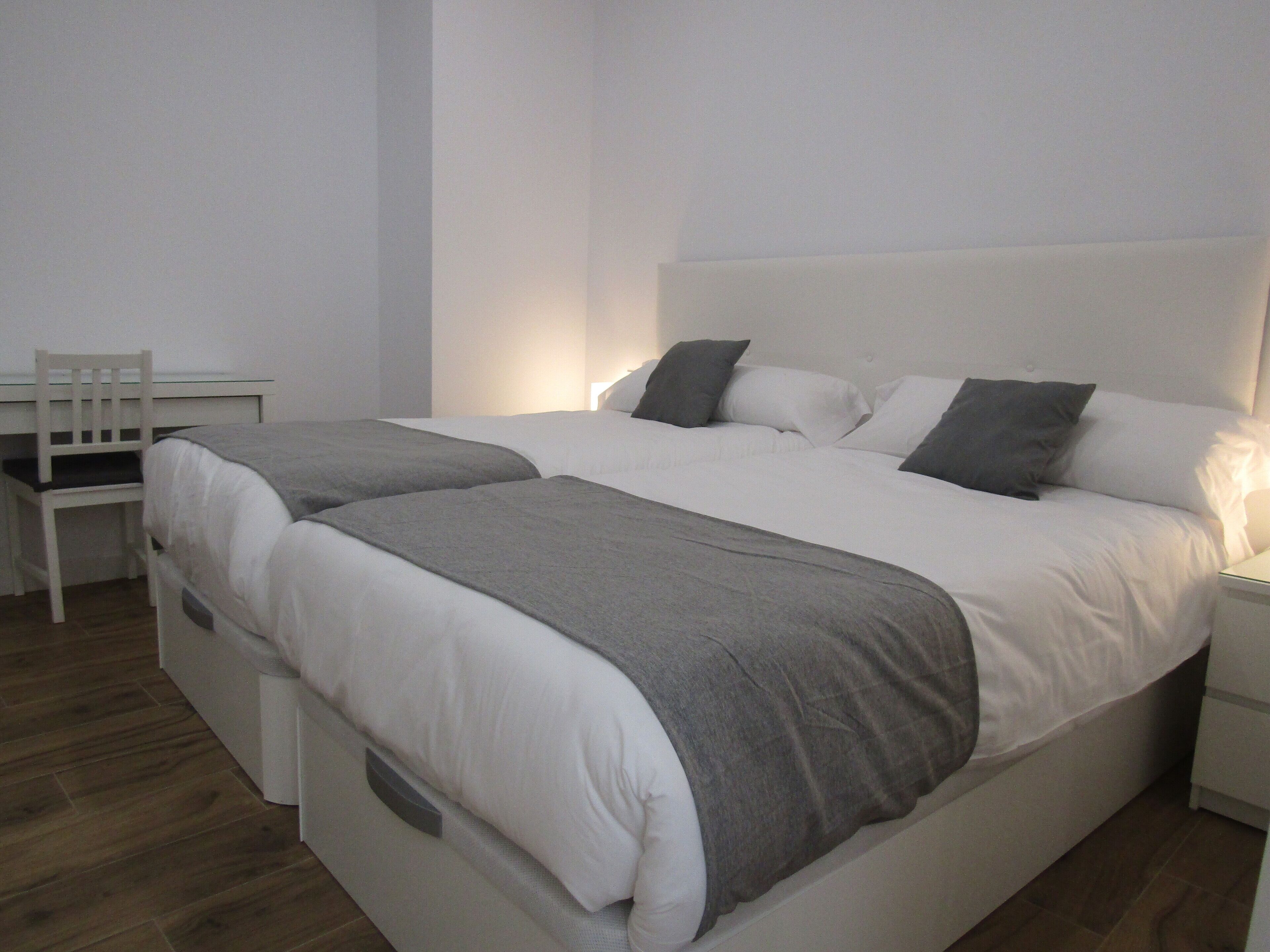 A modern bedroom with a large bed, a desk, and a chair.