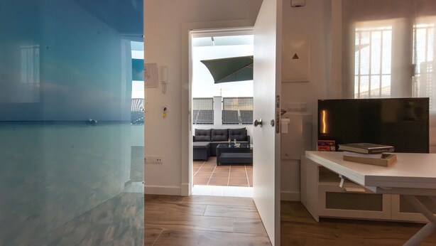 An open doorway leading to a living area with a sofa, a coffee table, and a TV stand. - Apartamentos Santa María 15 (Jerez de la Frontera)
