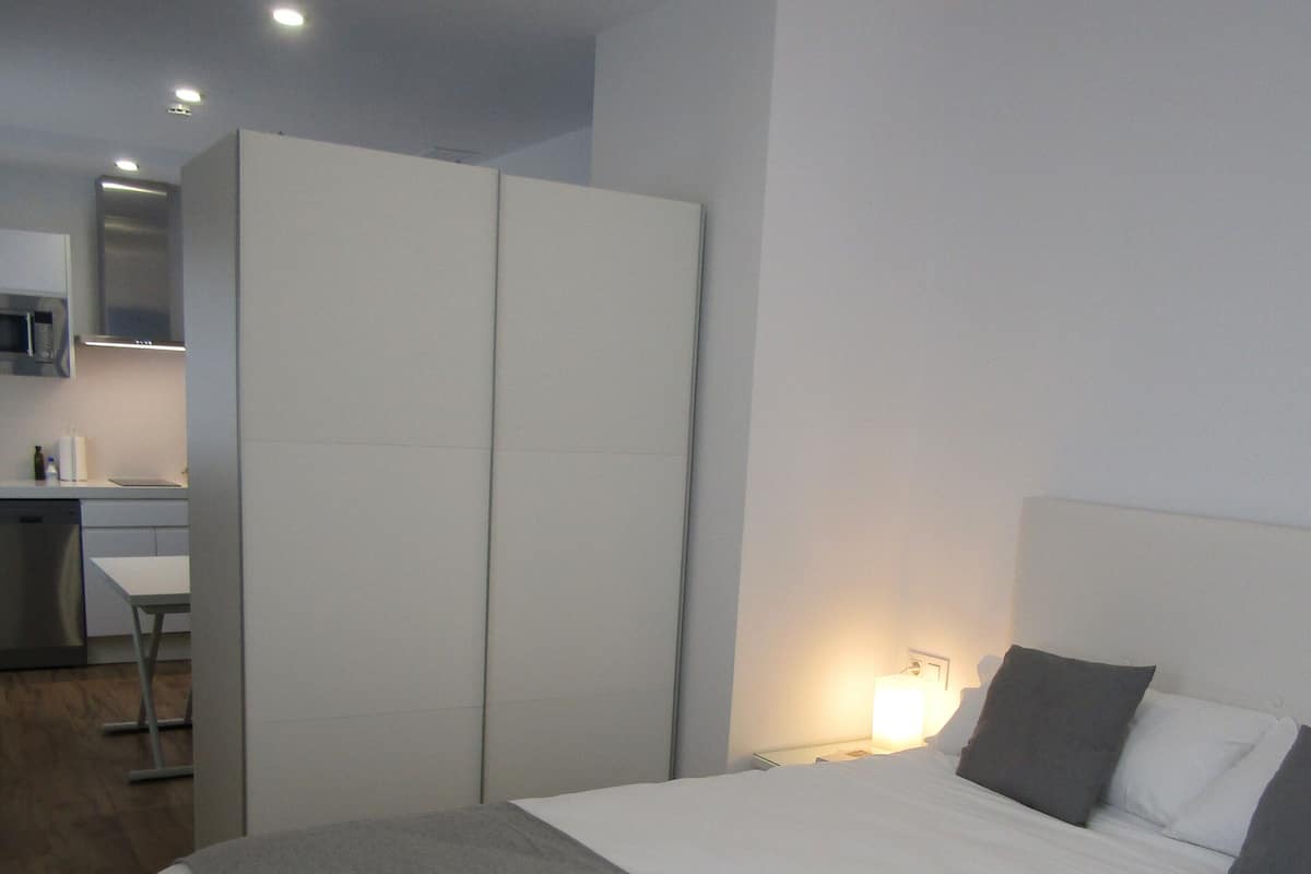 Een hotelkamer met een bed, een bureau en een kitchenette.