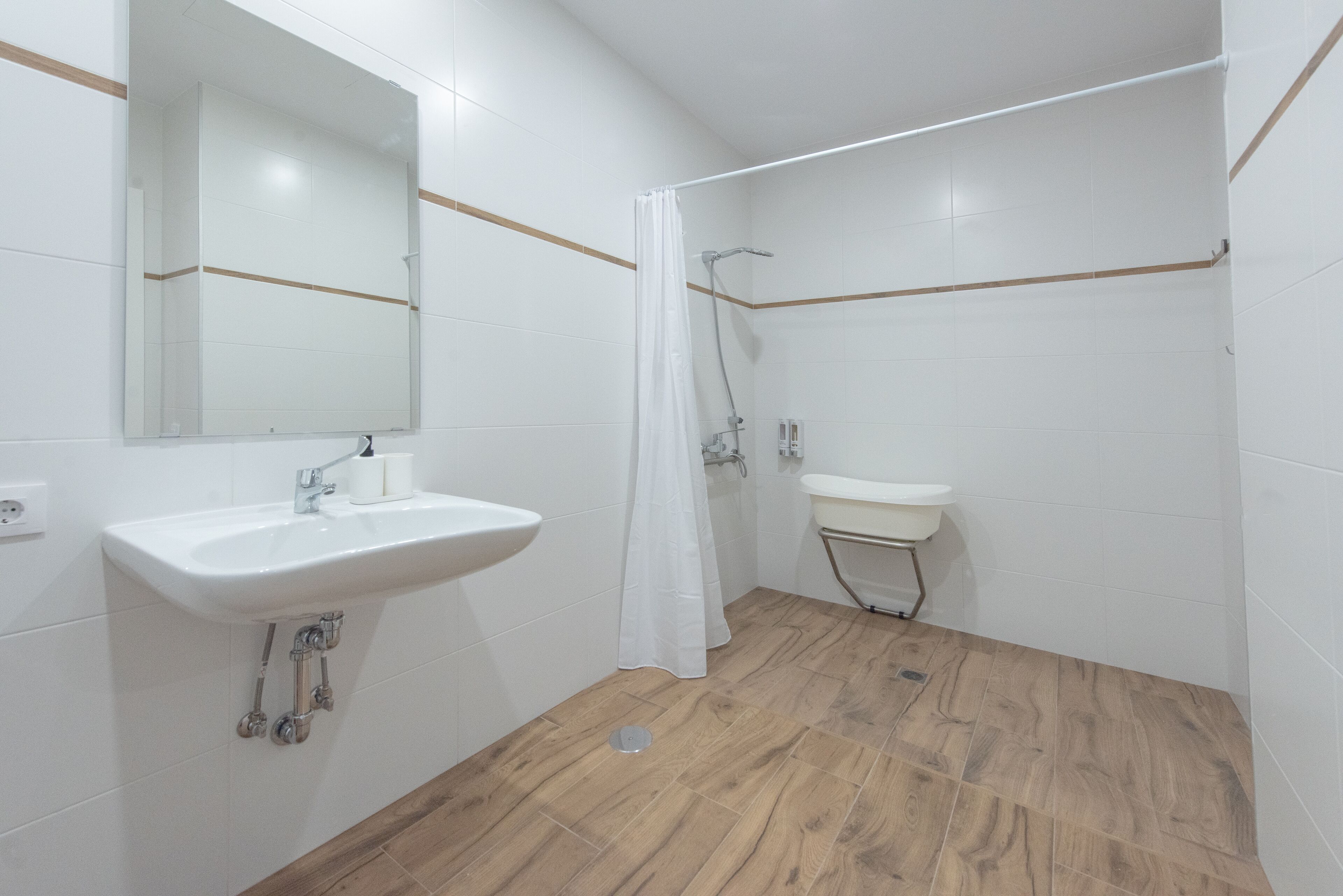 A bathroom with a white sink, mirror, and shower area.