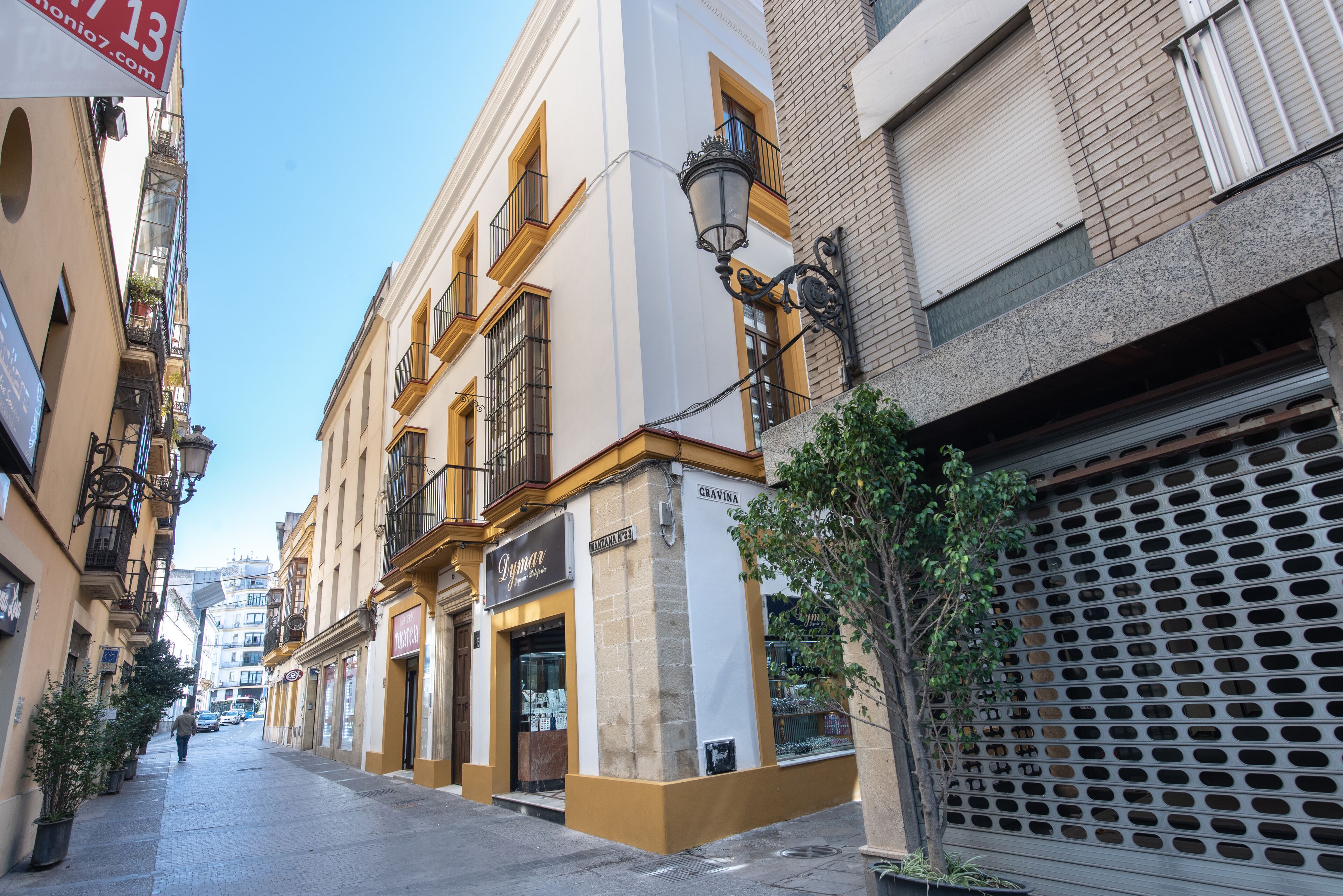 Una calle estrecha bordeada de edificios, incluyendo una tienda con un letrero que dice 'Gravina'.