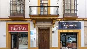 A building facade with two storefronts, one labeled 'Merceria Tocateja' and the other 'Dymar'. - Apartamentos Santa María 15 (Jerez de la Frontera)