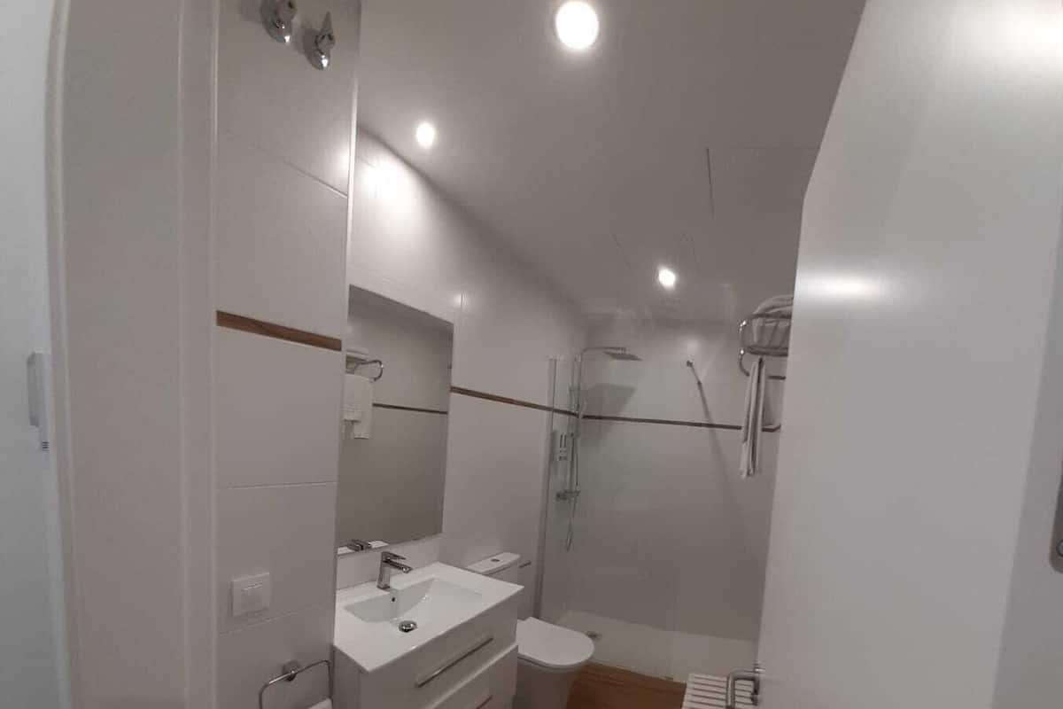Een moderne badkamer met douche, toilet en wastafel.