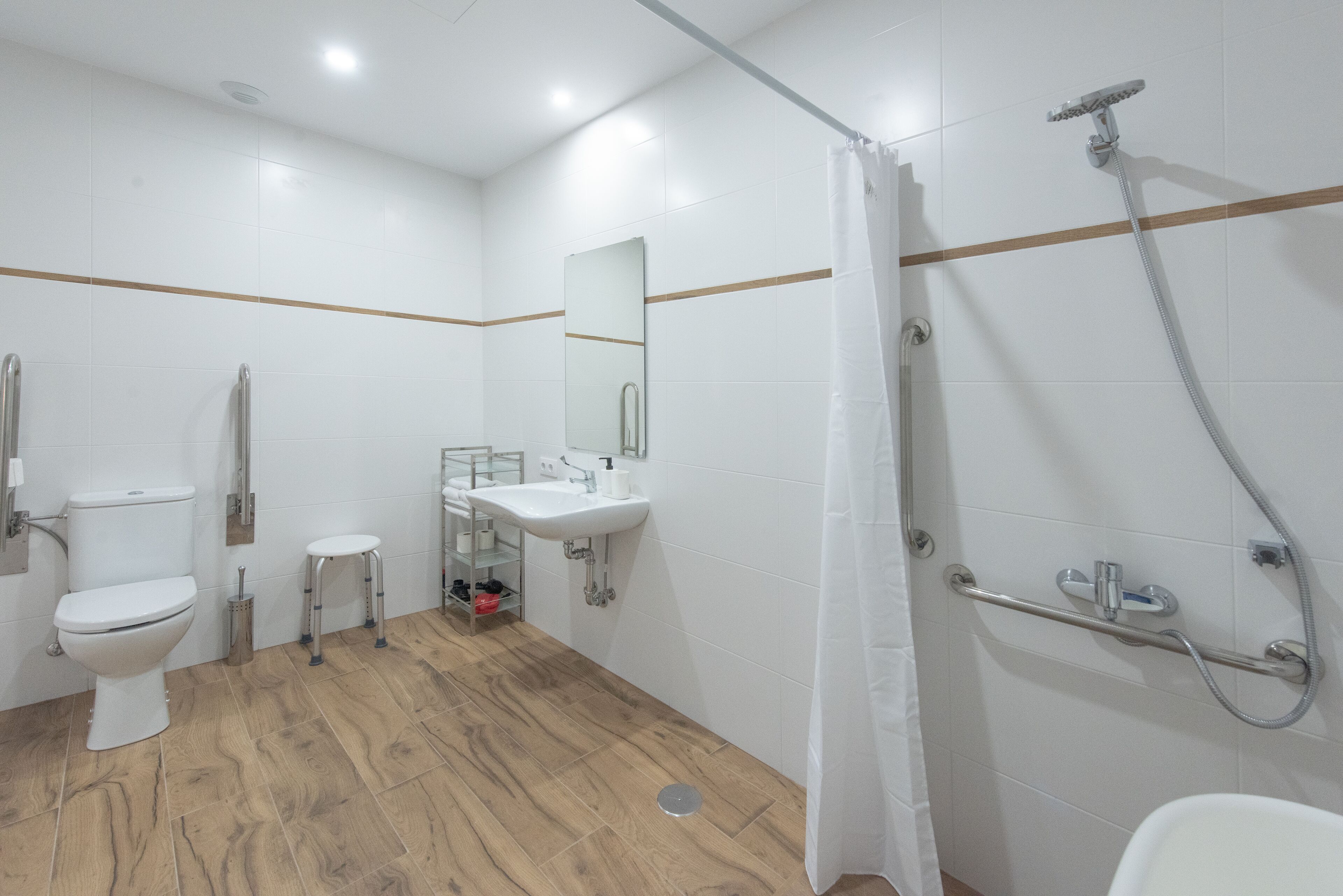 Un baño moderno con inodoro, lavamanos, ducha y suelo de madera.