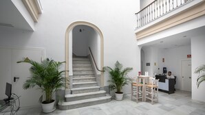 A spacious lobby with a marble staircase, potted plants, a reception desk, and a modern interior design. - Apartamentos Santa María 15 (Jerez de la Frontera)