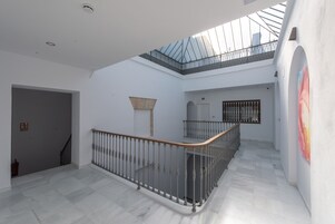 A spacious interior with a marble floor, a wooden railing, and a skylight.