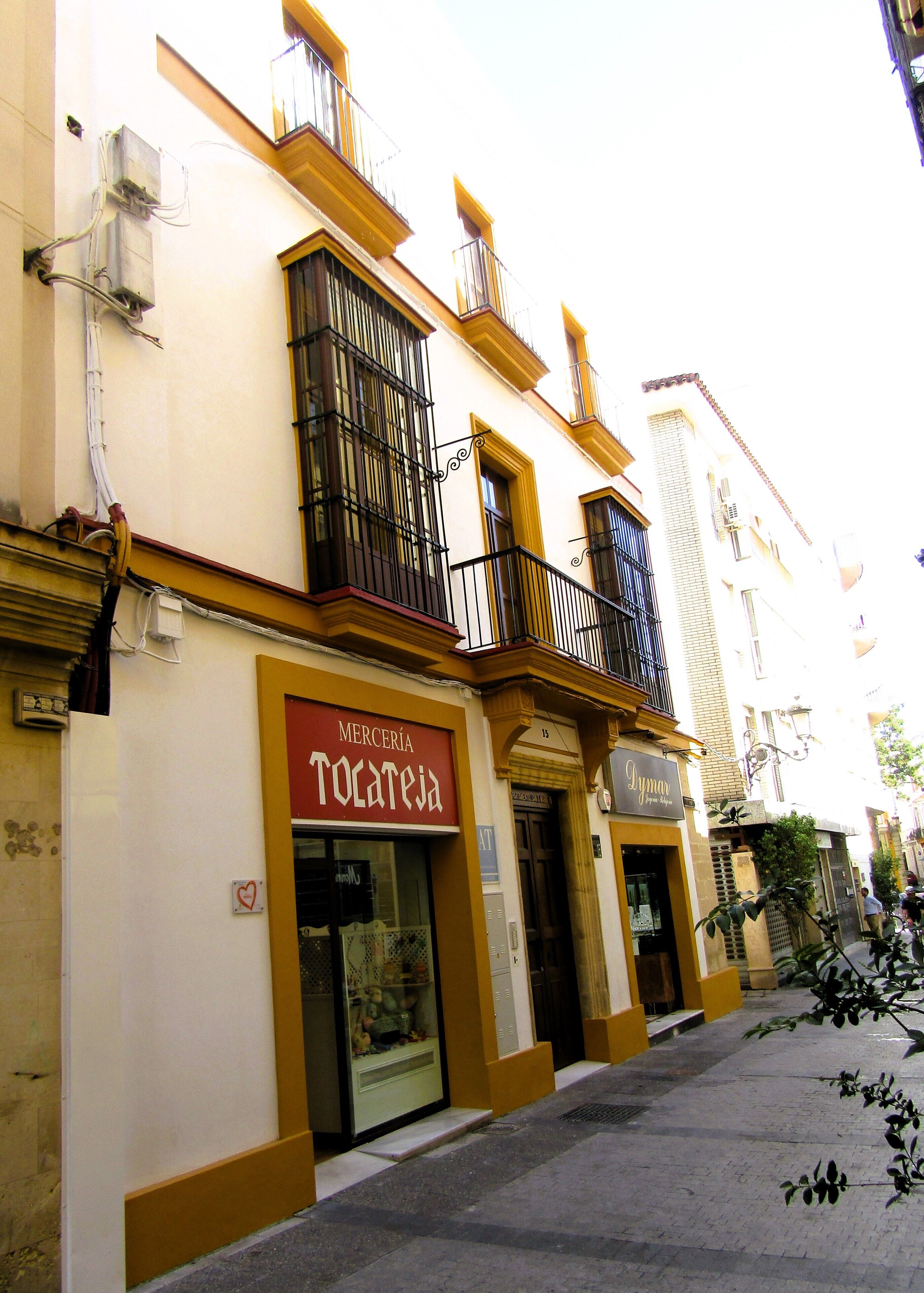 A street view with buildings, including a shop with a visible sign.