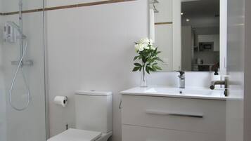 A modern bathroom with a toilet, a shower, and a vanity with a mirror.