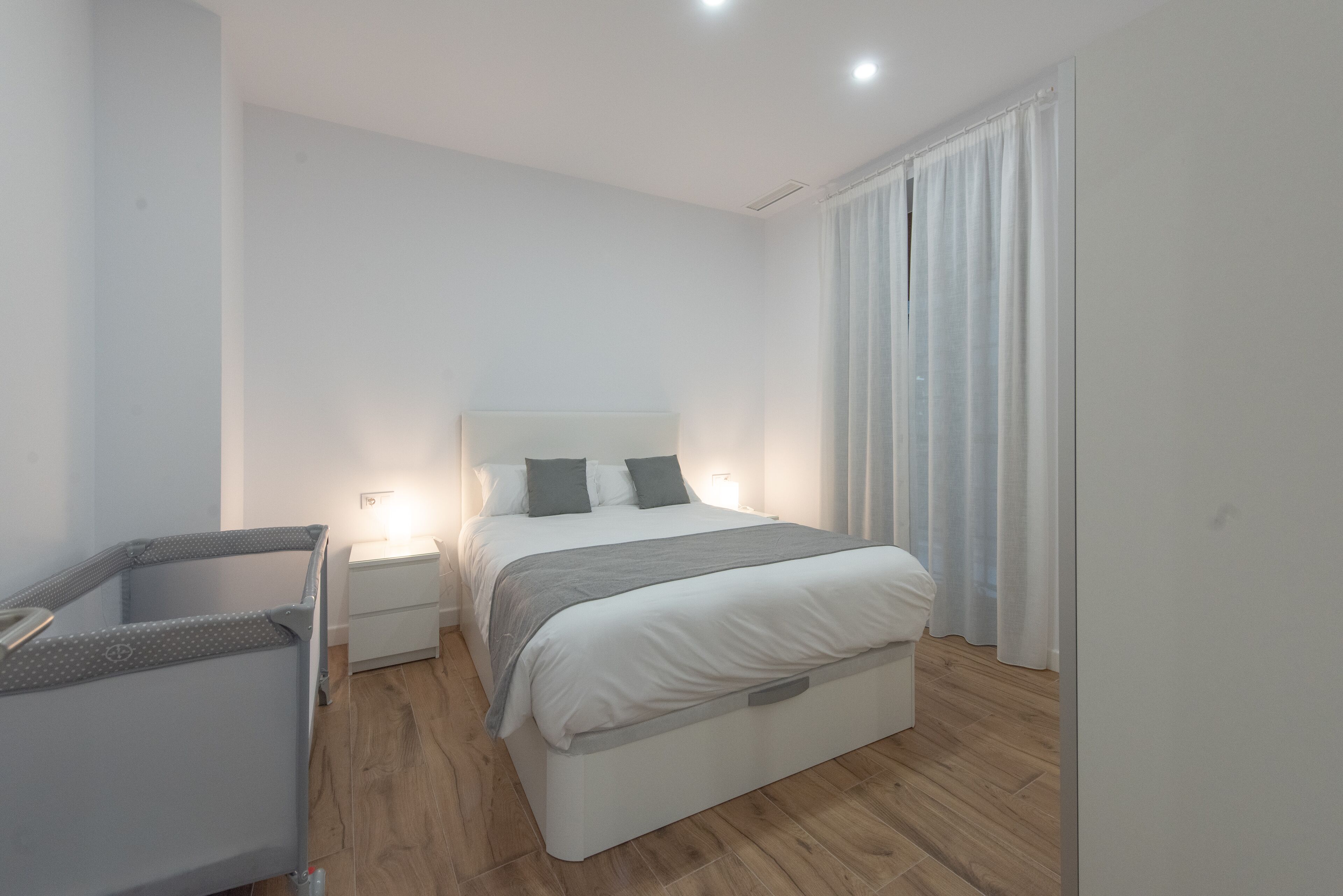 A modern bedroom with a bed, bedside tables, and a small seating area.
