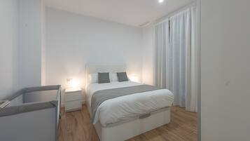 A modern bedroom with a bed, bedside tables, and a small seating area.
