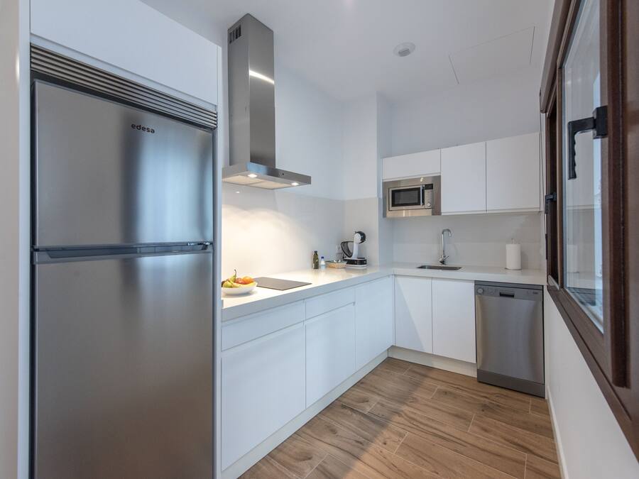 A modern kitchen with white cabinetry, a stainless steel refrigerator, a microwave, and a dishwasher.
