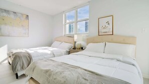 Habitación de hotel con dos camas, un ventanal grande, un cuadro y un marco en la pared.