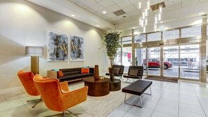 Un hall d’entrée moderne, avec un canapé, des fauteuils, une table basse et des œuvres d’art accrochées aux murs.