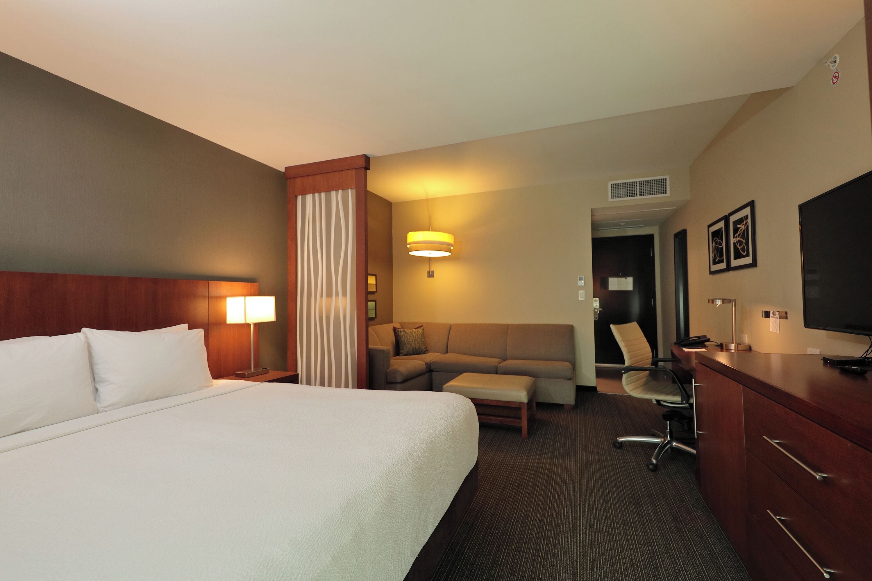 Una habitación de hotel con cama, escritorio, silla, sofá y televisión.