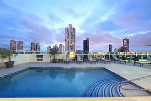 A rooftop pool with lounge chairs and a city skyline view. - Hotel Dann Carlton Panamá (Panama City)