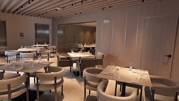 A modern restaurant interior with multiple dining tables and chairs, a wooden ceiling with recessed lighting, and a glass partition separating the dining area from the kitchen.