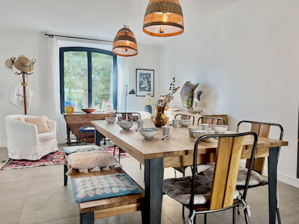 A dining area with a wooden table, chairs, and hanging pendant lights.