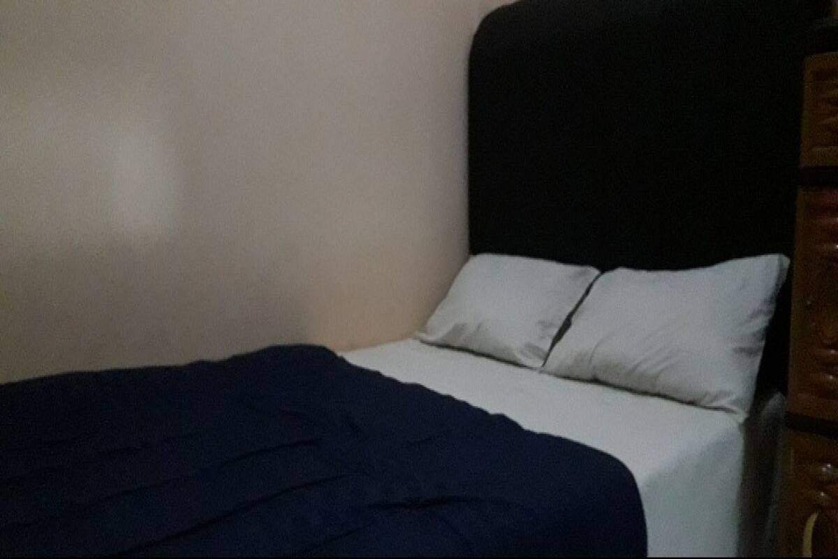 Una cama con un edredón azul oscuro y dos almohadas blancas.