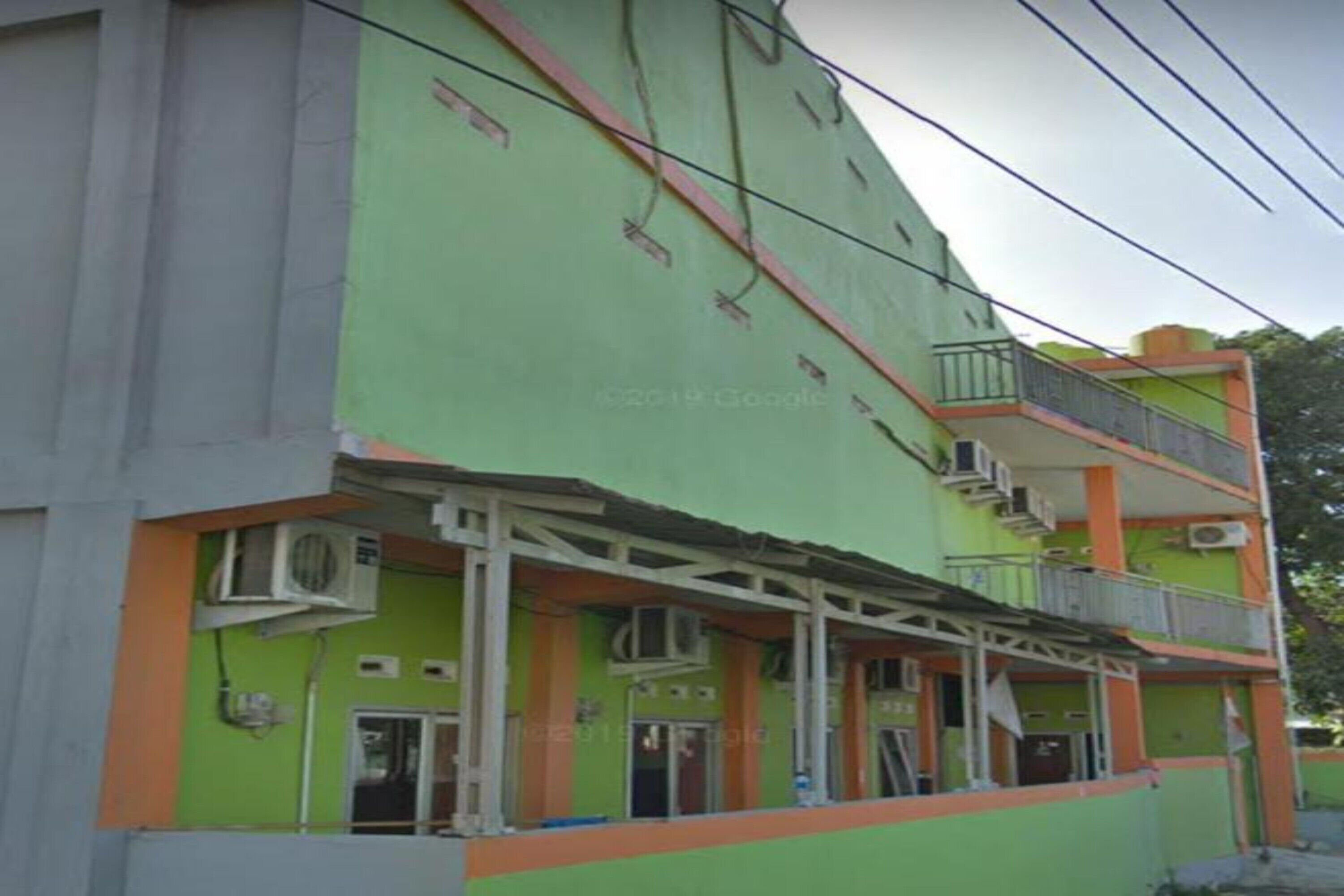 Un immeuble à plusieurs étages doté d’une façade verdoyante, de balcons et de climatiseurs.