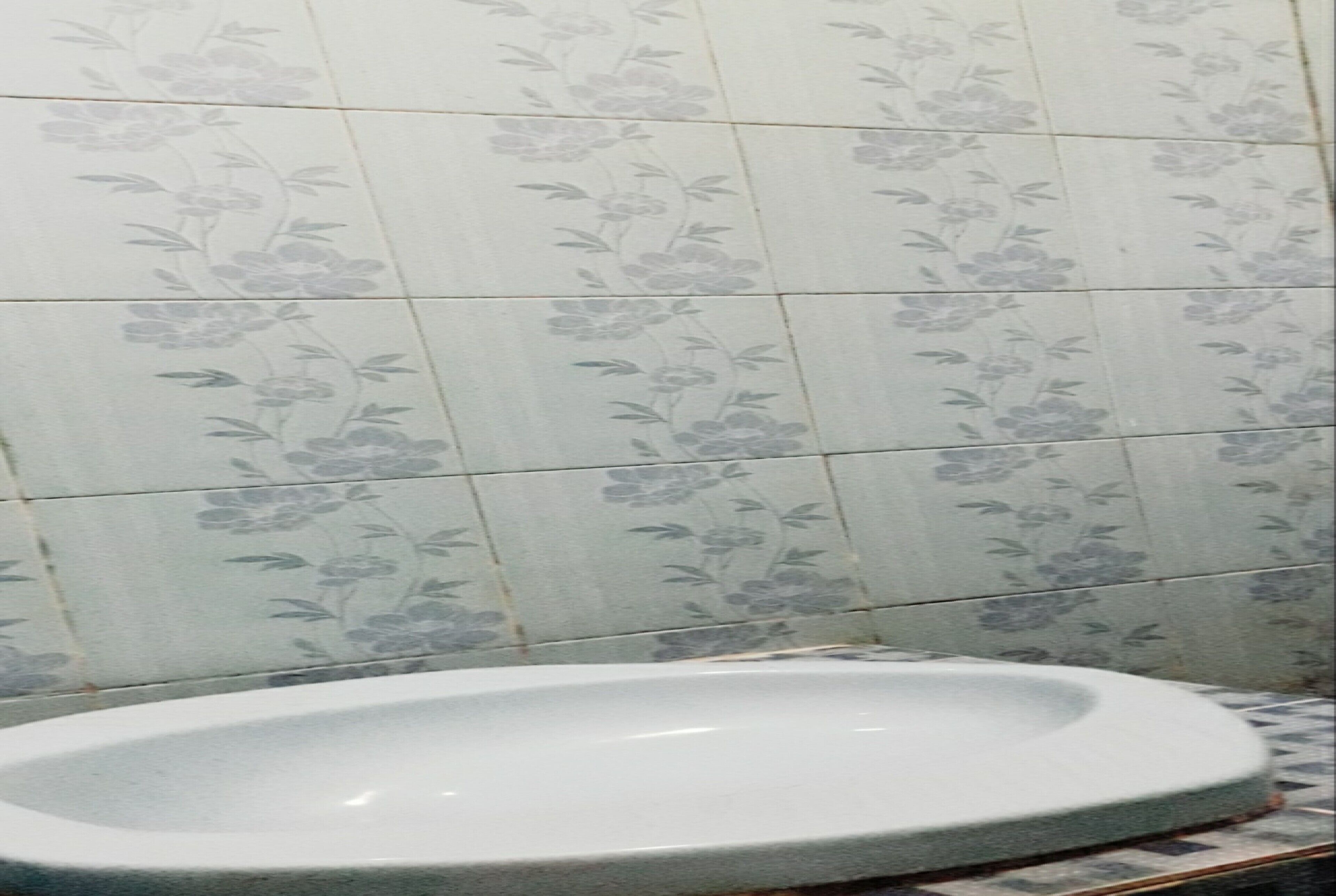 A bathroom with floral-patterned tiles and a white sink.