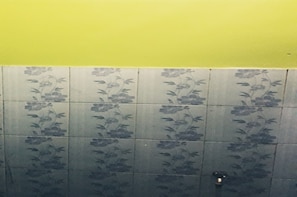 A bathroom with floral-patterned tiles and a yellow wall.
