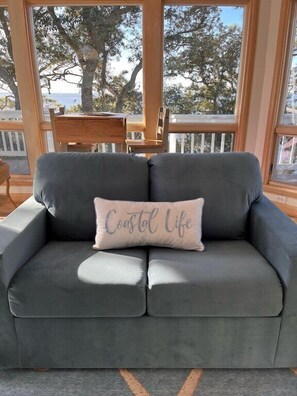 A grey sofa with a cushion that reads "Coastal Life" in cursive.