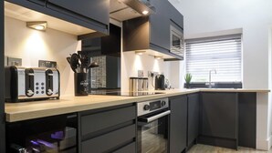 A modern kitchen with a built-in oven, a coffee machine, and a toaster. - Beam End Snainton - Modern 2-bedroom Stone Cottage. Pet Friendly. (Snainton)