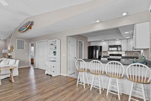 A modern kitchen with white cabinets, a black refrigerator, and a stainless steel stove.