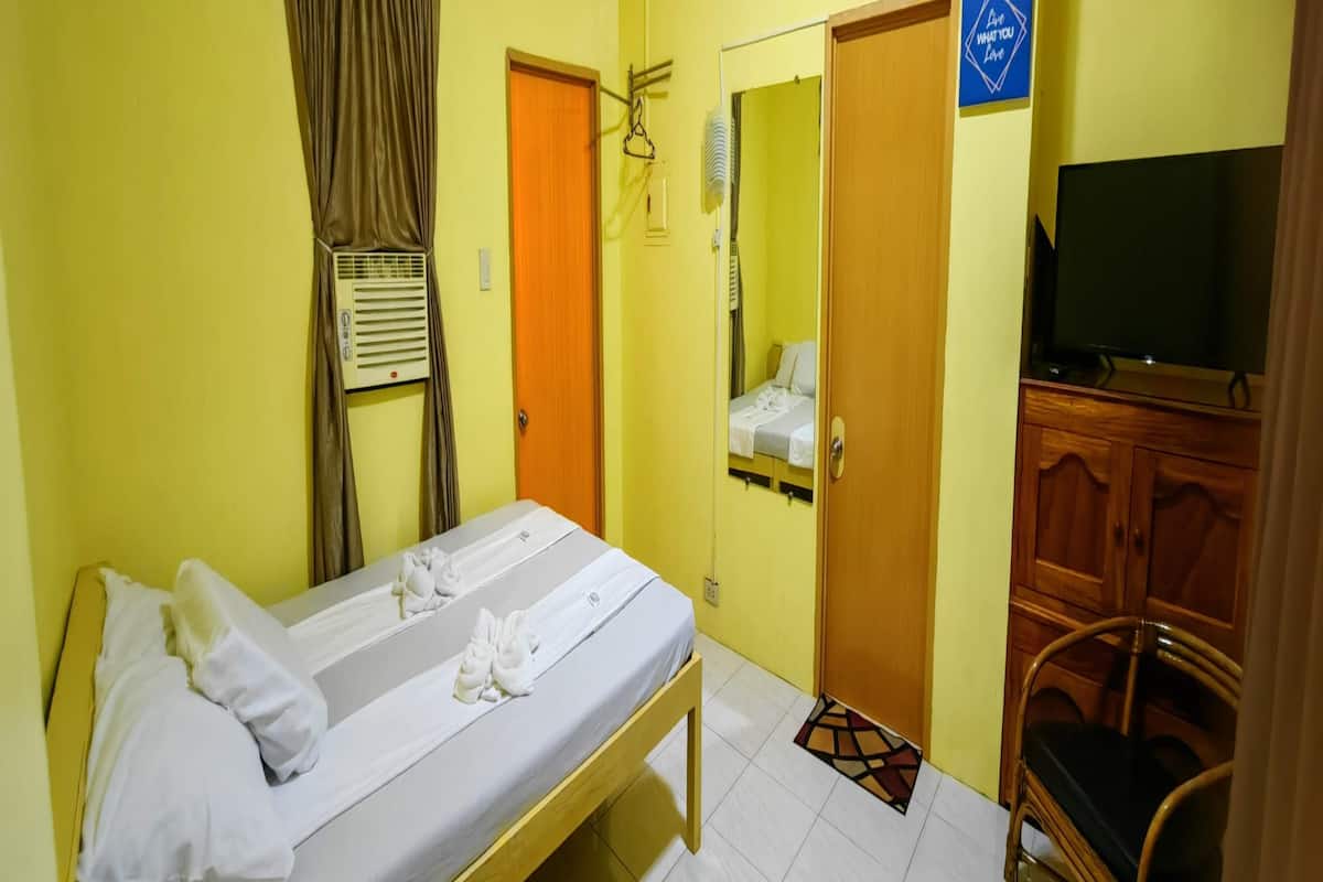 Habitació d'hotel amb llit, televisió, armari i mirall.