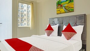 Ein Hotelzimmer mit Bett, einem Vorhangfenster, einem Gemälde an der Wand und Blick auf ein Gebäude.