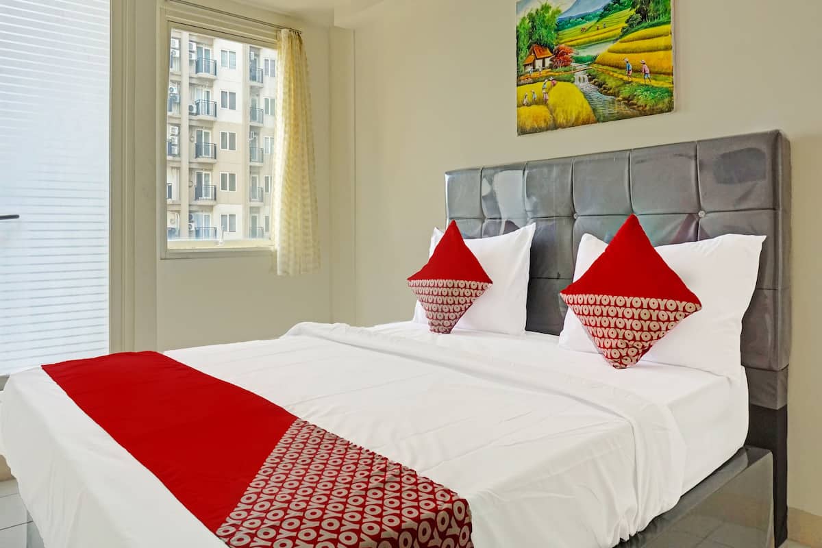 Une chambre d’hôtel avec un lit, une fenêtre avec des rideaux, un tableau au mur et une vue sur un bâtiment à l’extérieur.