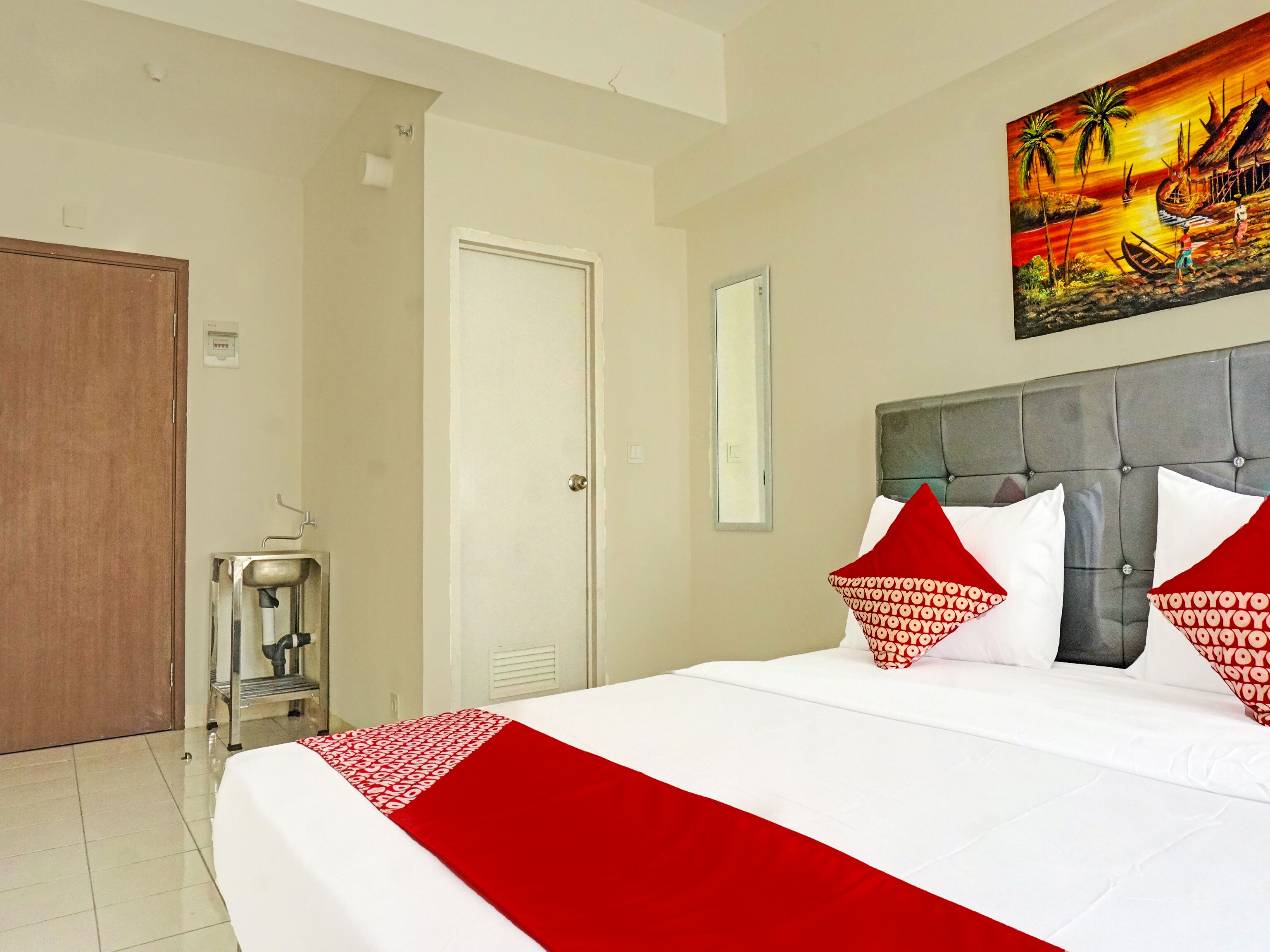 A hotel room with a large bed, a painting on the wall, and a water dispenser.